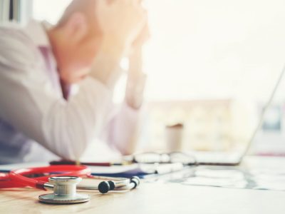 Stethoscope and doctor sitting with laptop stress headache about work in hospital